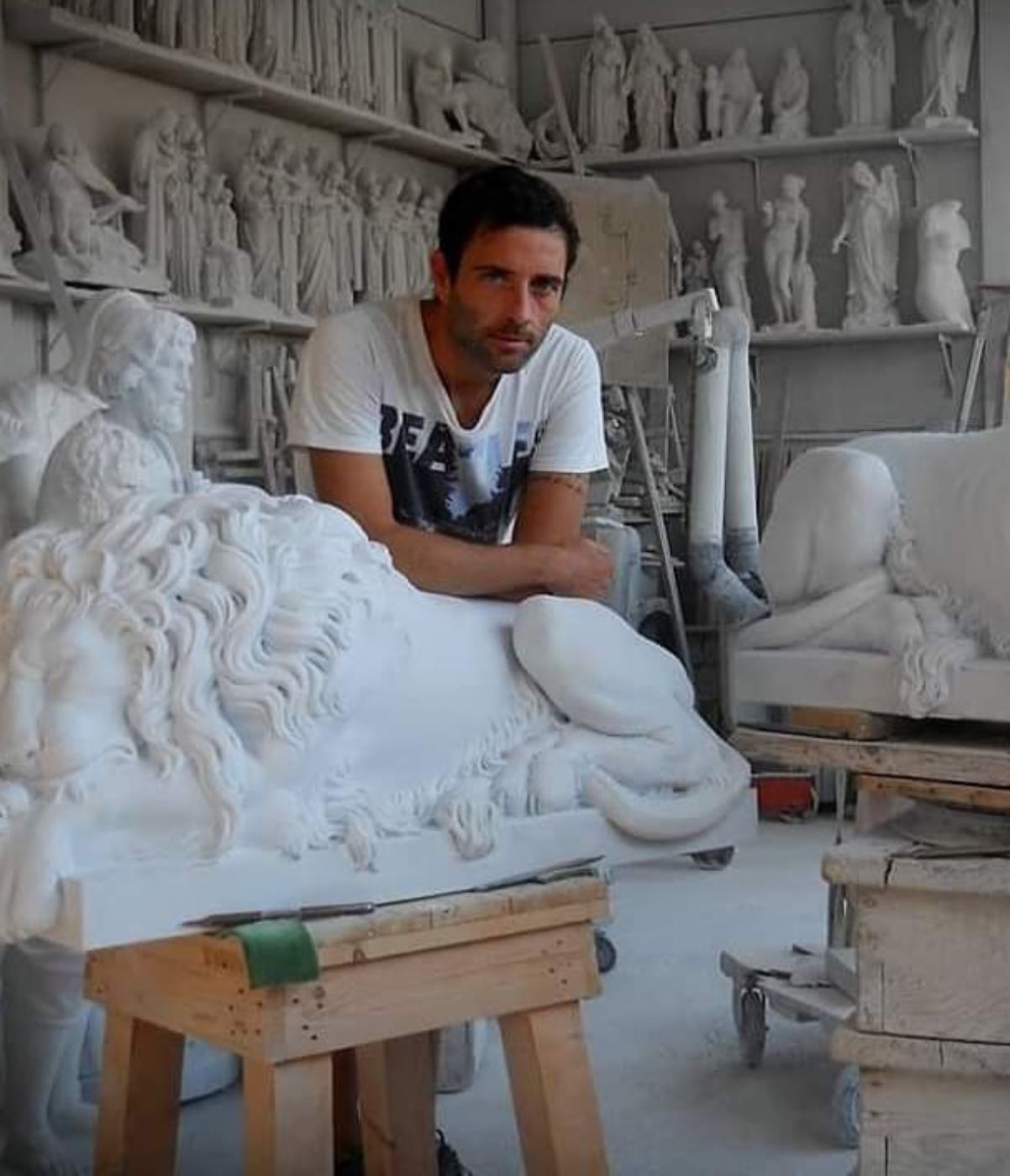 Sculptor Alberto Giannoni beside an unfinished marble lion sculpture, Pietrasanta studio