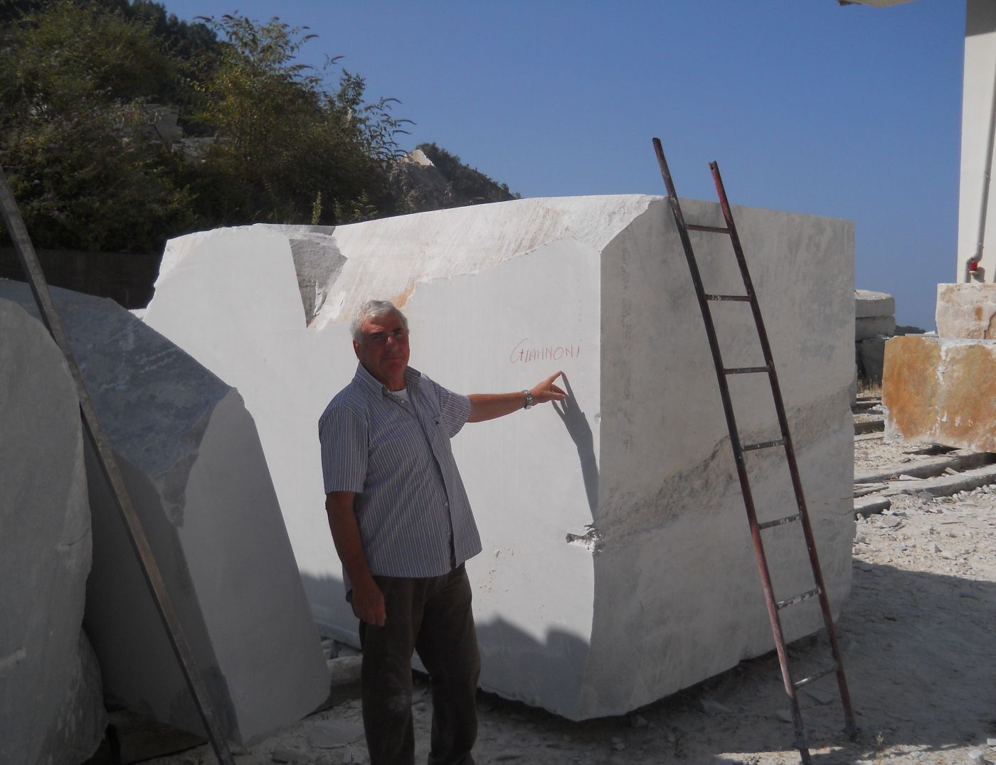 Ulderigo Giannoni inspecting a raw Carrara marble block marked with the family name, before cutting