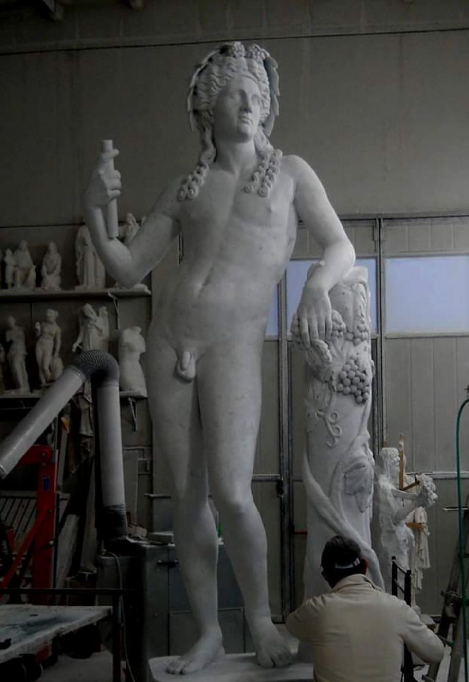 Hand-finished Carrara marble reproduction of the Bacchus Richelieu, artisan finishing the vine-draped support at Studio Giannoni, Pietrasanta