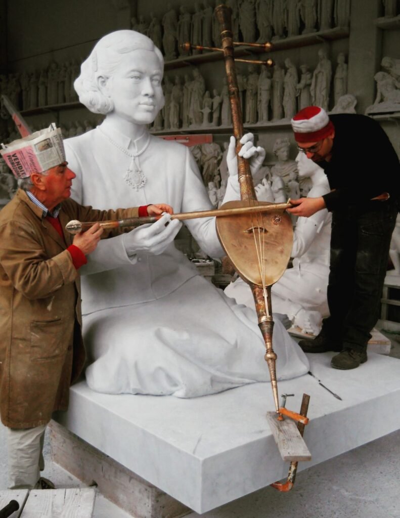 Ulderigo and Alberto Giannoni measuring a marble statue with a traditional musical instrument in their Pietrasanta atelier